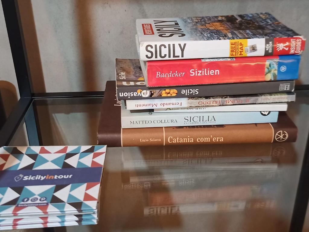 stos książek siedzących na szklanym stole w obiekcie Cortile Pantaleone Holiday Home w Katanii