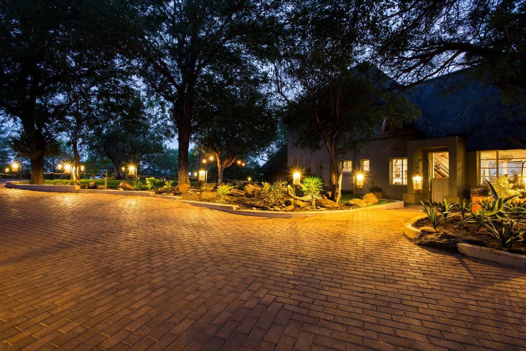 une rue pavée avec des arbres et des lumières la nuit dans l'établissement isiLimela Game Lodge, à Hoedspruit