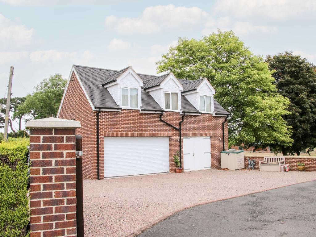 uma casa de tijolos com duas portas de garagem brancas em Springfield House em Stafford