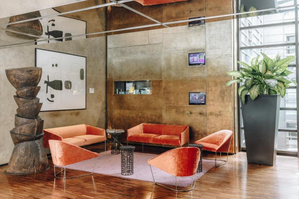 a lobby with orange chairs and a potted plant at DelleArti Design Hotel in Cremona