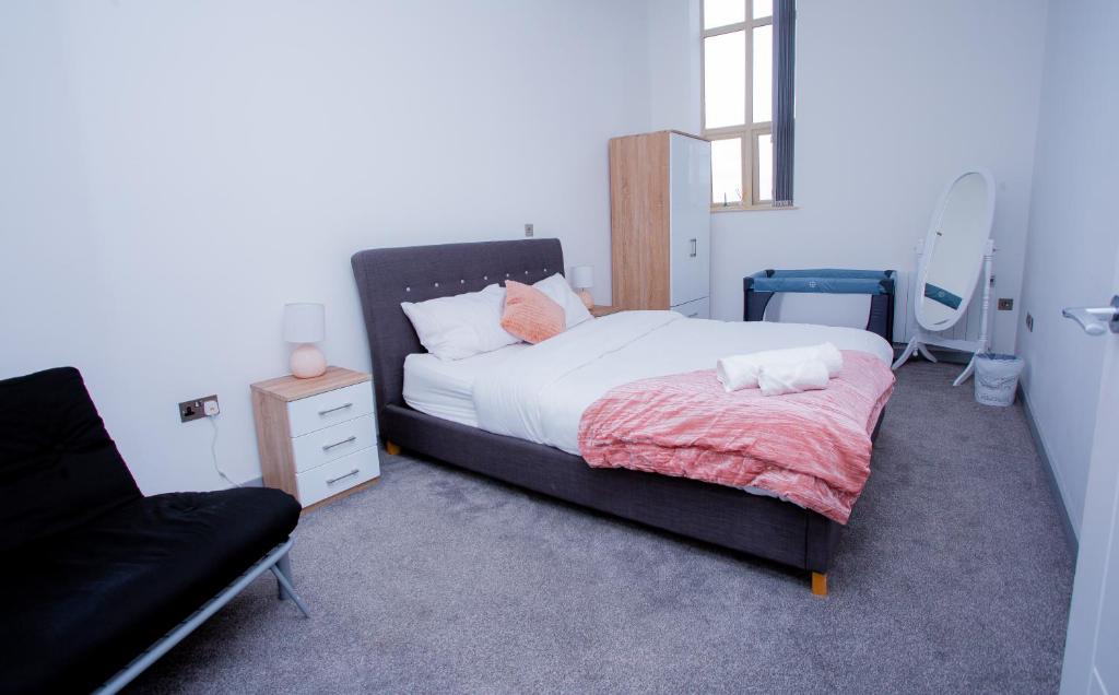 a bedroom with a bed and a chair in it at Spacious Urban City Apartment in Doncaster