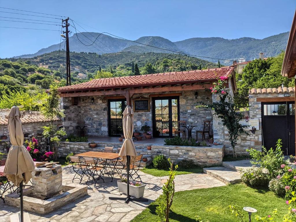 een stenen huis met een tafel en parasols in de tuin bij Bahab Guest House in Doğanbey