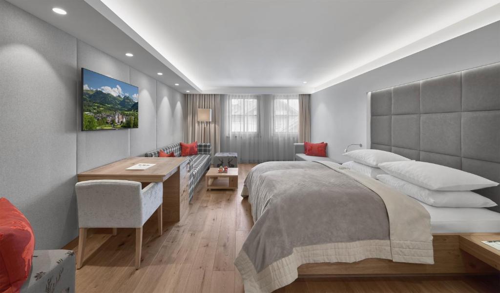 a bedroom with a large bed and a desk at Schwarzer Adler Kitzbühel - Adults Only in Kitzbühel