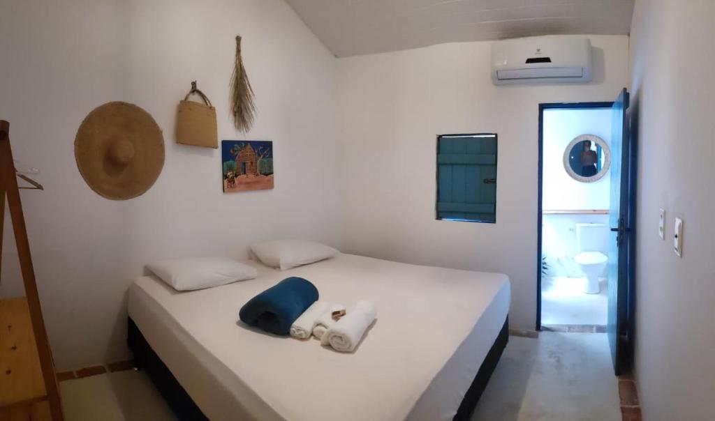 Un dormitorio con una cama blanca con un sombrero azul. en CASA PIPA BG en Barra Grande