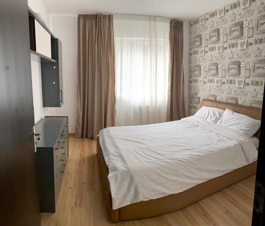 AMG Apartament في براشوف: غرفة نوم بسرير ابيض ونافذة