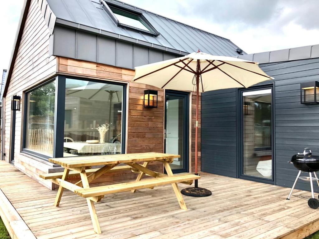 una terraza de madera con mesa de picnic y sombrilla en Nouveau: La cabine du bout du monde - Petit Minou - : votre pied-à-terre breton haut standing [PL01], en Crozon