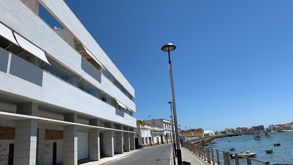 a street next to a building next to a body of water at Mirador de la ría, Isla Cristina in Isla Cristina