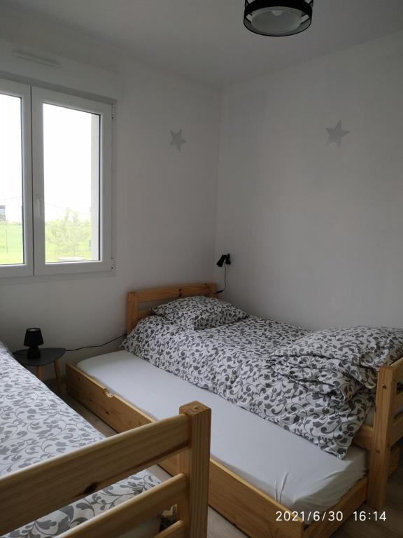 two beds in a room with white walls and a window at Gite du patureau in Belleray