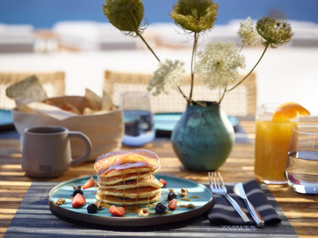 a plate of pancakes and berries on a table at Domes White Coast Milos, Adults Only - Small Luxury Hotels of the World in Mytakas