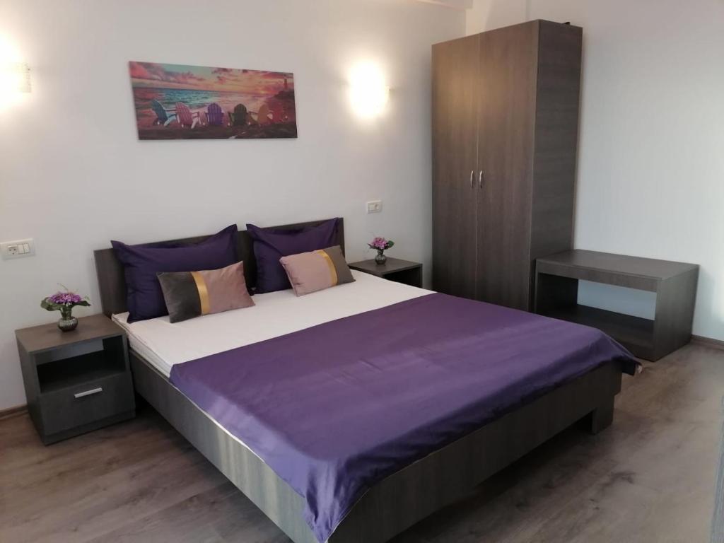 ママイア・ノルドにあるApartament Porto Del Marのベッドルーム1室(紫のシーツが敷かれた大型ベッド1台付)