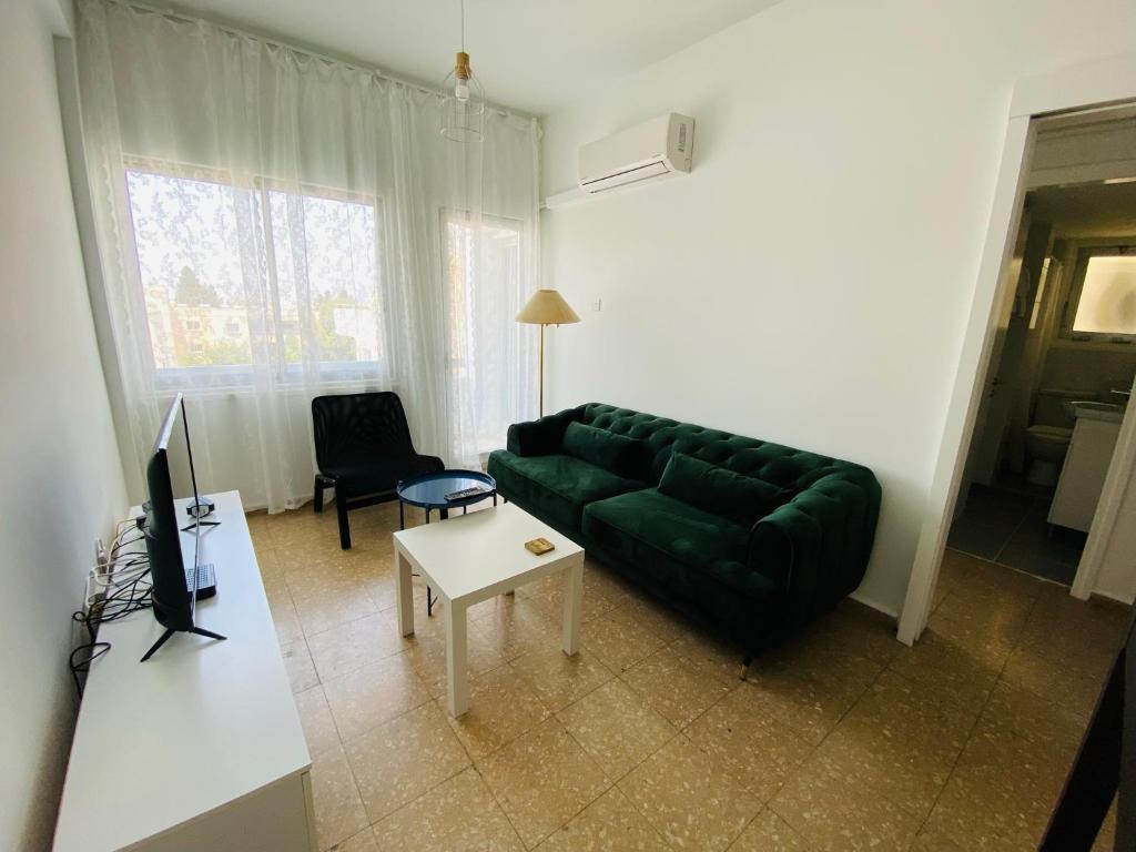 ein Wohnzimmer mit einem grünen Sofa und einem Tisch in der Unterkunft Simple One bedroom flat in Engomi in İncirli