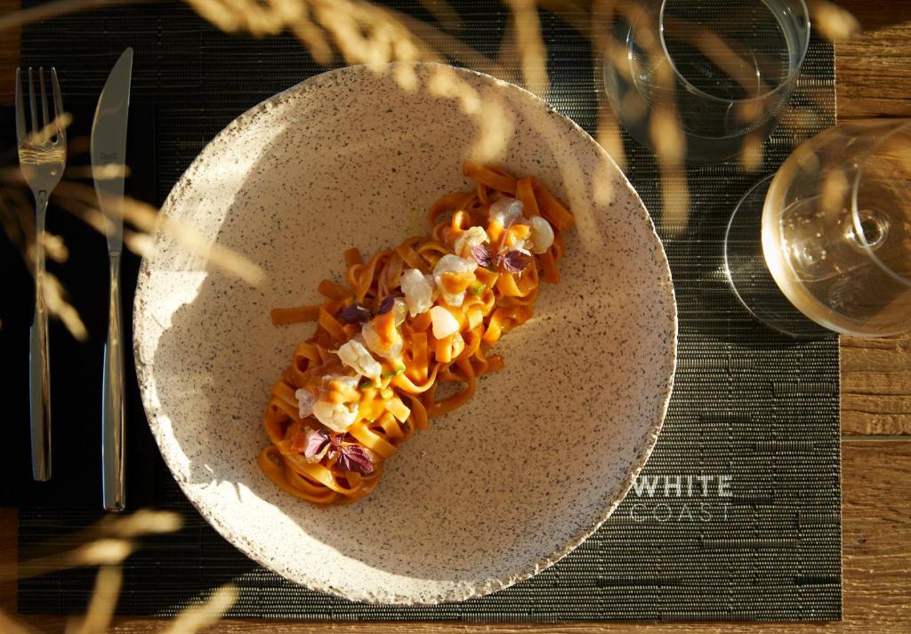 a white plate with food on a table at Domes White Coast Milos, Adults Only - Small Luxury Hotels of the World in Mytakas