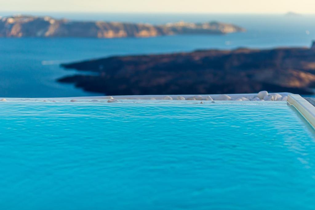 een zwembad met uitzicht op de oceaan bij Santorini Delux in Imerovígli