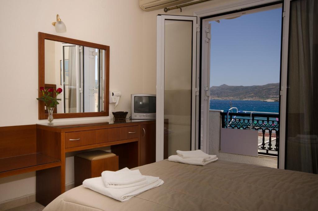 a bedroom with a desk and a mirror and a bed at Hotel El Greco in Sitia