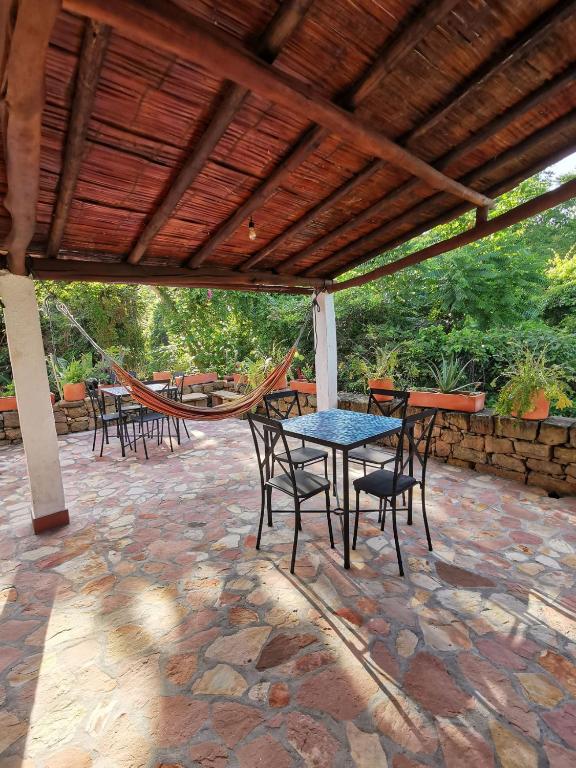 a patio with a table and chairs and a hammock at Las Cabezas Grises in Barichara