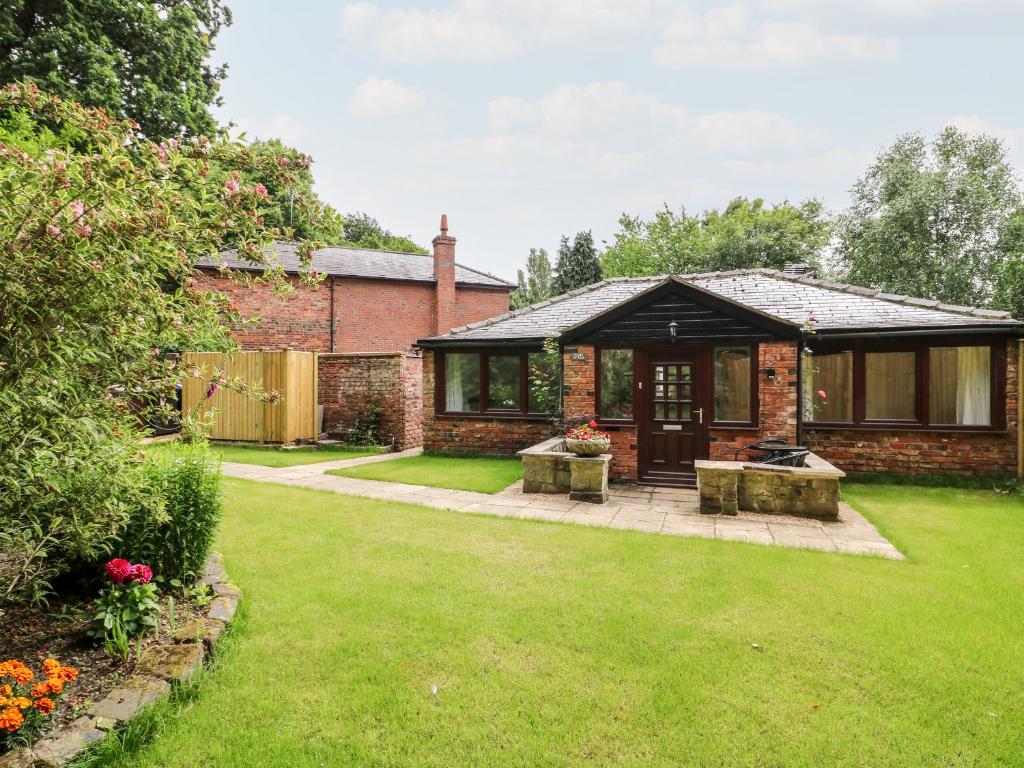 a brick house with a patio and a yard at Claire Cottage in Selby