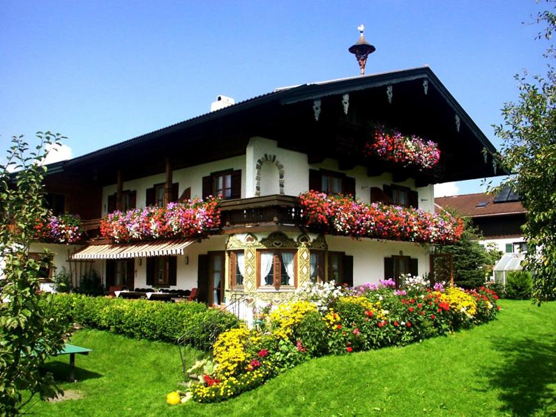 un bâtiment avec beaucoup de fleurs devant lui dans l'établissement Gästehaus Restner - Chiemgau Karte, à Inzell