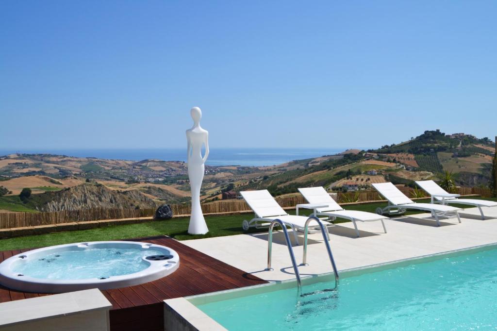 a villa with a swimming pool with a statue and chairs at B&B & SPA Novantadieci Club in Atri