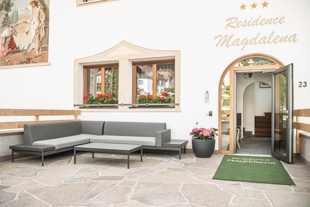 eine Terrasse mit einem Sofa und einem Tisch vor einem Gebäude in der Unterkunft Residence Magdalena in St. Ulrich in Gröden