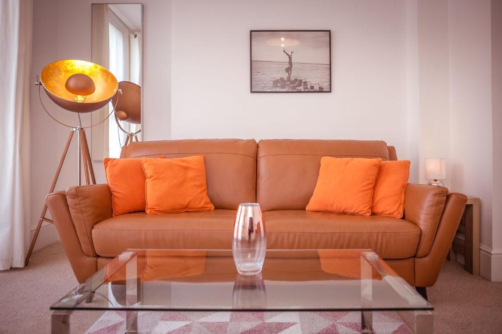 a living room with a brown couch and a glass table at Little Chelsea Beacon - chic & central flat with parking in Eastbourne