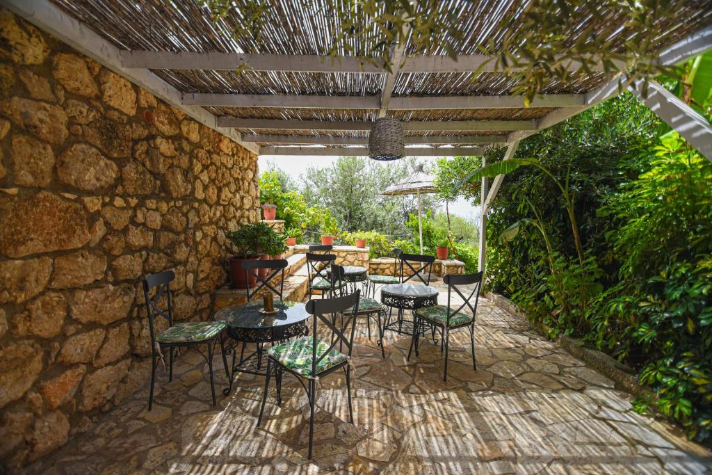 a patio with tables and chairs under a stone wall at Hotel Imperial in Dhërmi
