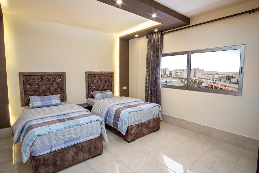 two beds in a room with a window at Al Riyati Hotel Apartments in Aqaba