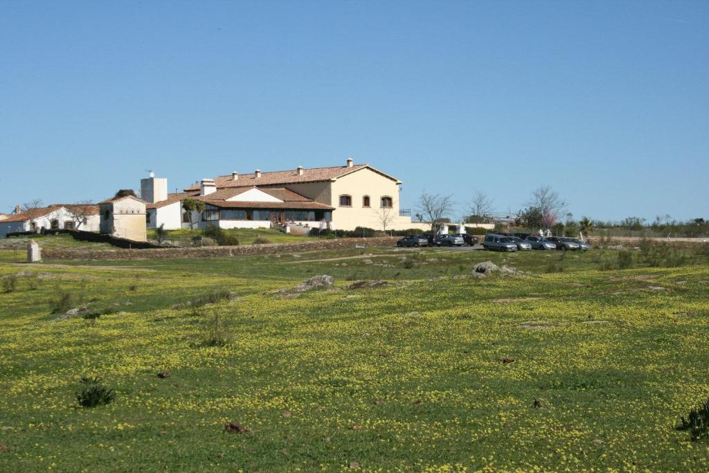 a field of green grass with a house in the background at Casa Rural Las Canteras in Trujillo