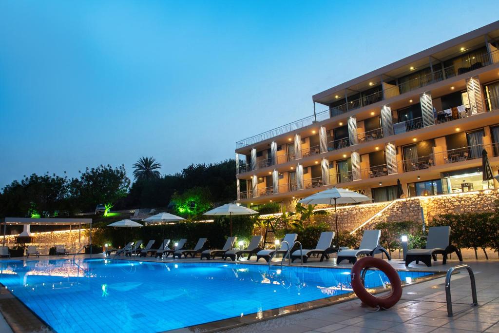 a hotel with a swimming pool in front of a building at Apollon Hotel in Tolo