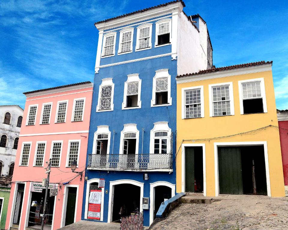 a blue building with white windows on a street at Pousada Cor e Arte - Pelourinho in Salvador