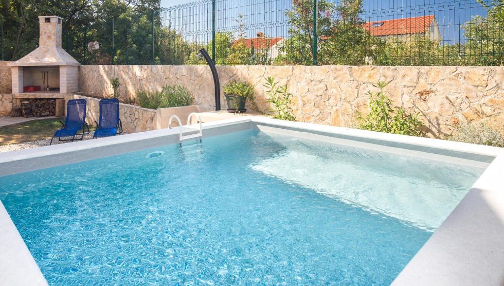 a swimming pool with blue chairs and a stone wall at Apartment Mar in Kostrena