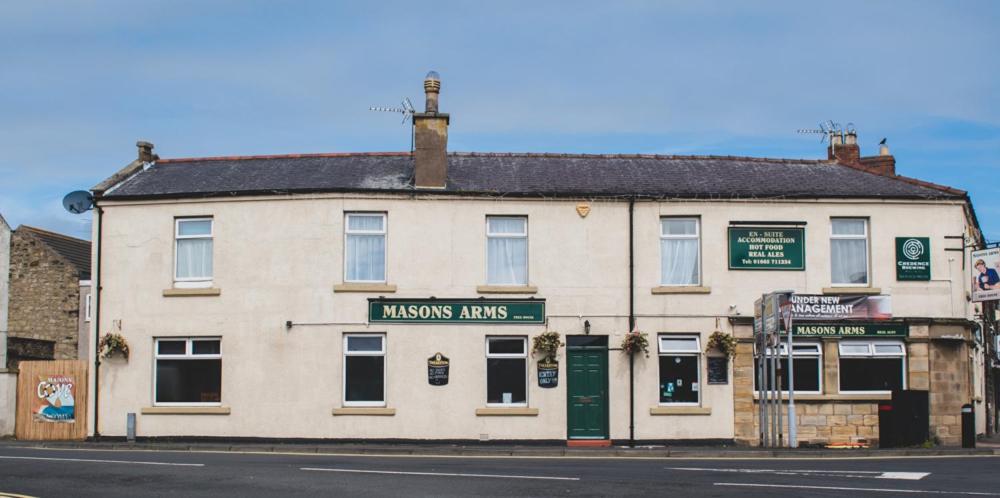 a large white building on the corner of a street at Masons Arms Amble in Amble