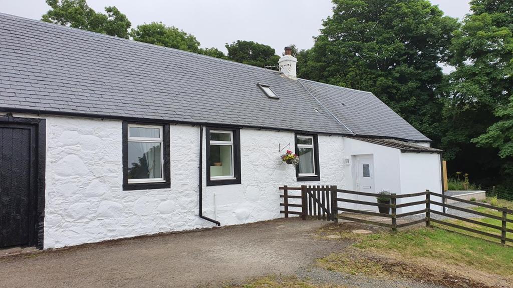 un edificio bianco con un gatto seduto sopra di Dairy Cottage with sea views a Girvan