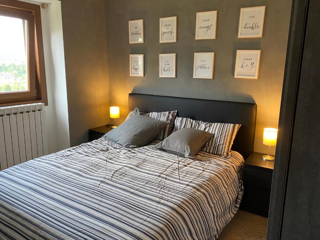 a bedroom with a bed with two pillows and two lamps at Be Smiling Appartament in Passo del Tonale