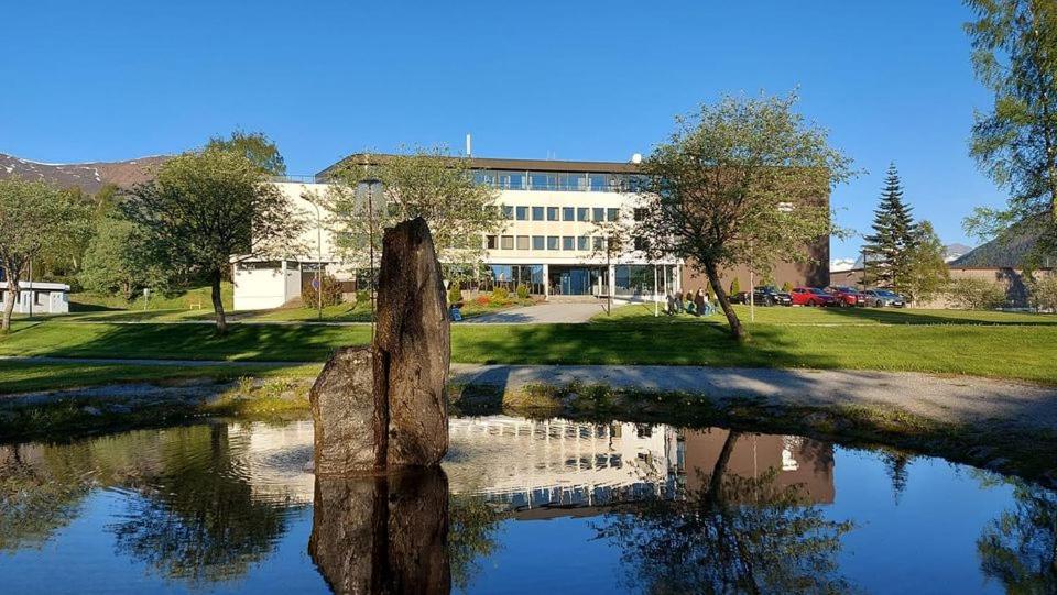 un reflejo de un edificio en un cuerpo de agua en Havila Hotel Ivar Aasen en Ørsta