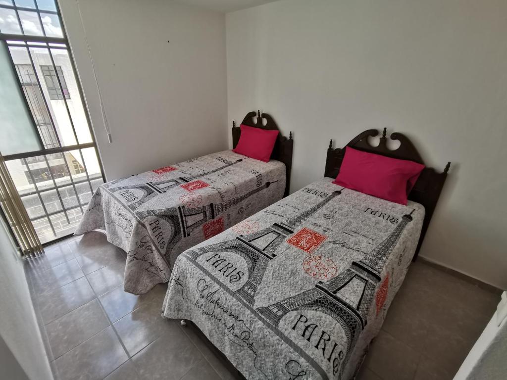 2 camas en una habitación con almohadas rojas en Casa Magnolia Queretaro TODO INCLUIDO, en Querétaro