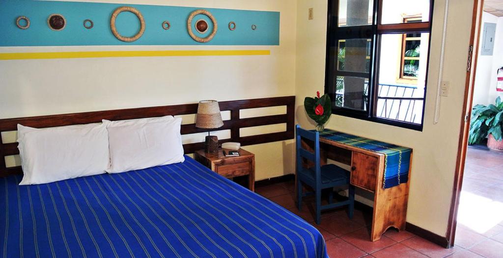 a bedroom with a blue bed and a desk at Arbol de Fuego Eco-hotel in San Salvador