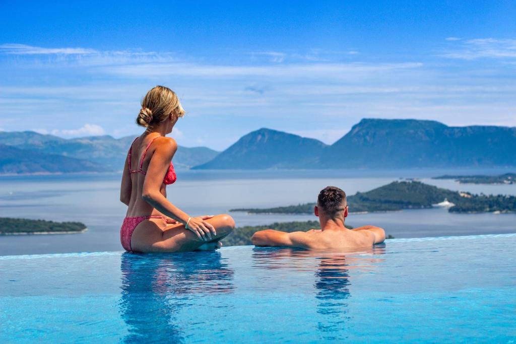 a man and a woman sitting in a infinity pool at Desun Suites in Kolónion