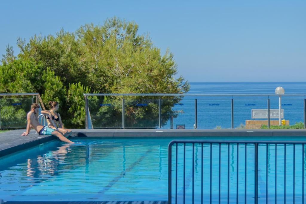 dos personas sentadas en el borde de una piscina en Albatros Family, en Salou