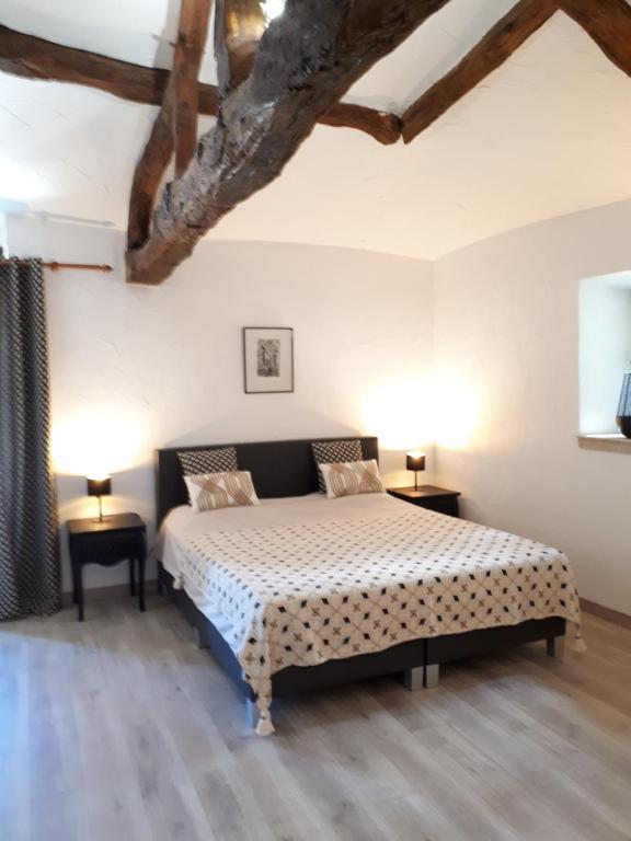 1 dormitorio con 1 cama, 2 mesas y 2 lámparas en Domaine de Merugat Chambre d'Hôtes, en Valeilles