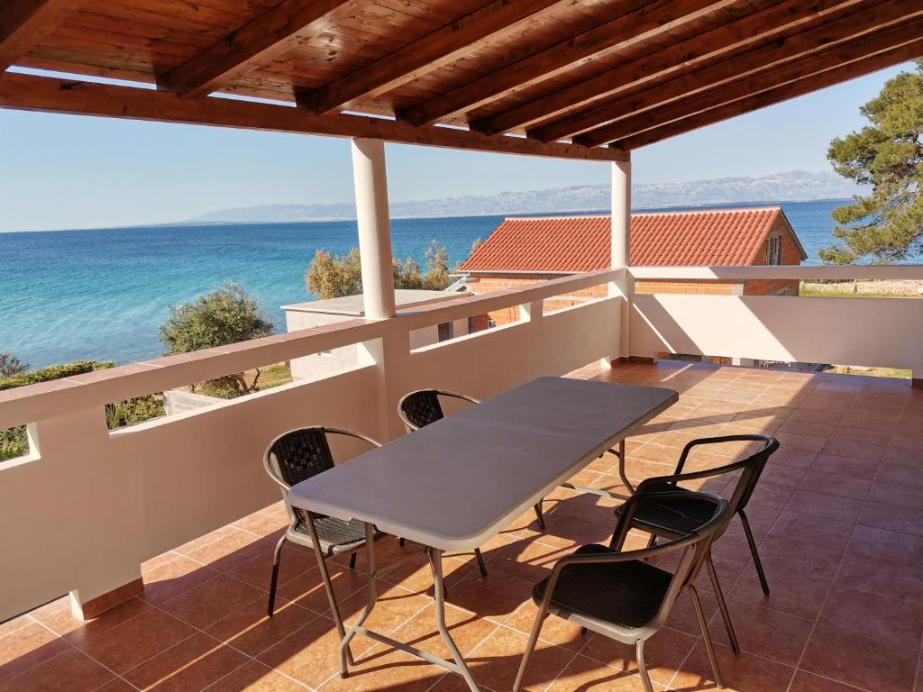 uma mesa e cadeiras numa varanda com vista para o oceano em Apartment Porat em Ugljan