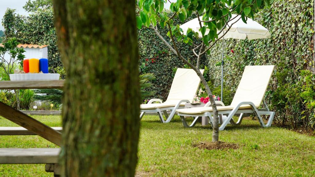 ポンタ・デルガダにあるCasa da Horta Açoresの白い椅子2脚と木の横の傘