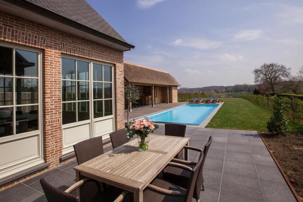 um pátio com uma mesa e cadeiras de madeira e uma piscina em Vakantiewoning Nr63 em Brakel