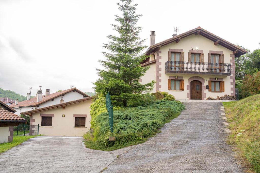 una casa con un árbol al lado de una carretera en Casa rural Gibelea y Gibelea Txiki en Viscarret-Guerendiáin