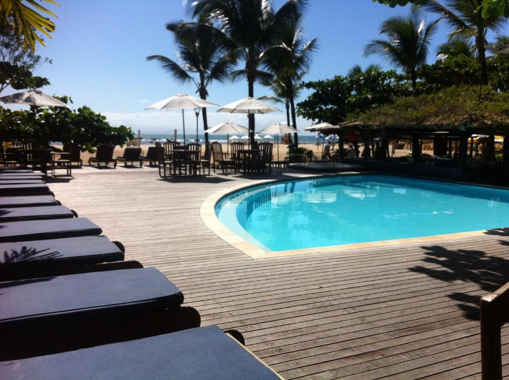 uma piscina com cadeiras e guarda-sóis num deque de madeira em Via Das Pedras Pousada em Morro de São Paulo