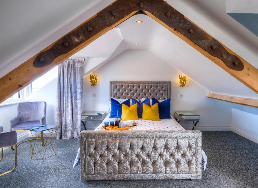 a bedroom with a bed with blue and yellow pillows at The Rockpool - private hot tub and sea views in Amble