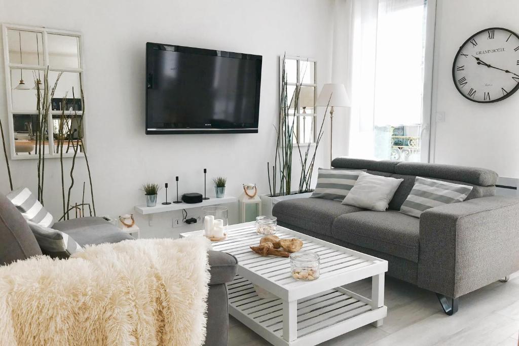 ein Wohnzimmer mit einem Sofa, einem Tisch und einem TV in der Unterkunft Gare - Les Champs - 1 SDB privative - parking gratuit in Saint-Brieuc
