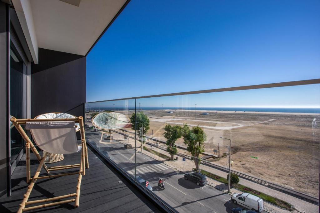a rocking chair on a balcony looking out at the beach at Acqua House by Rent4All in Figueira da Foz