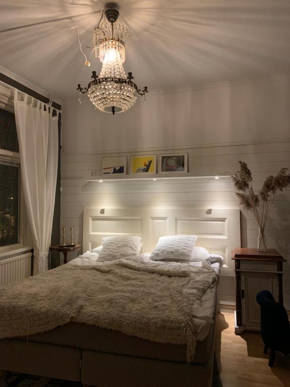 a bedroom with a large bed and a chandelier at Stensö Room in Kalmar