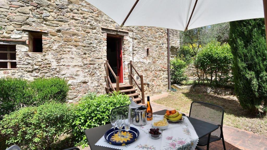 einen Tisch mit einem Teller Essen und einem Regenschirm in der Unterkunft Raffaello in Gaiole in Chianti