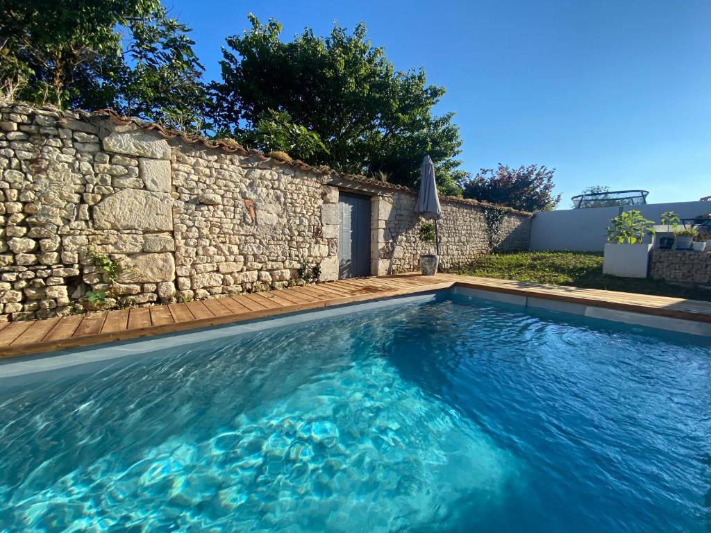 uma piscina em frente a uma parede de pedra em Suite pour deux em La Jarne